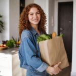 Smiling woman carrying grocery bag at home